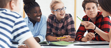 Ensino Fundamental II – 4 crianças entre 10 e 14 anos, em ambiente escolar conversando com uma professora.